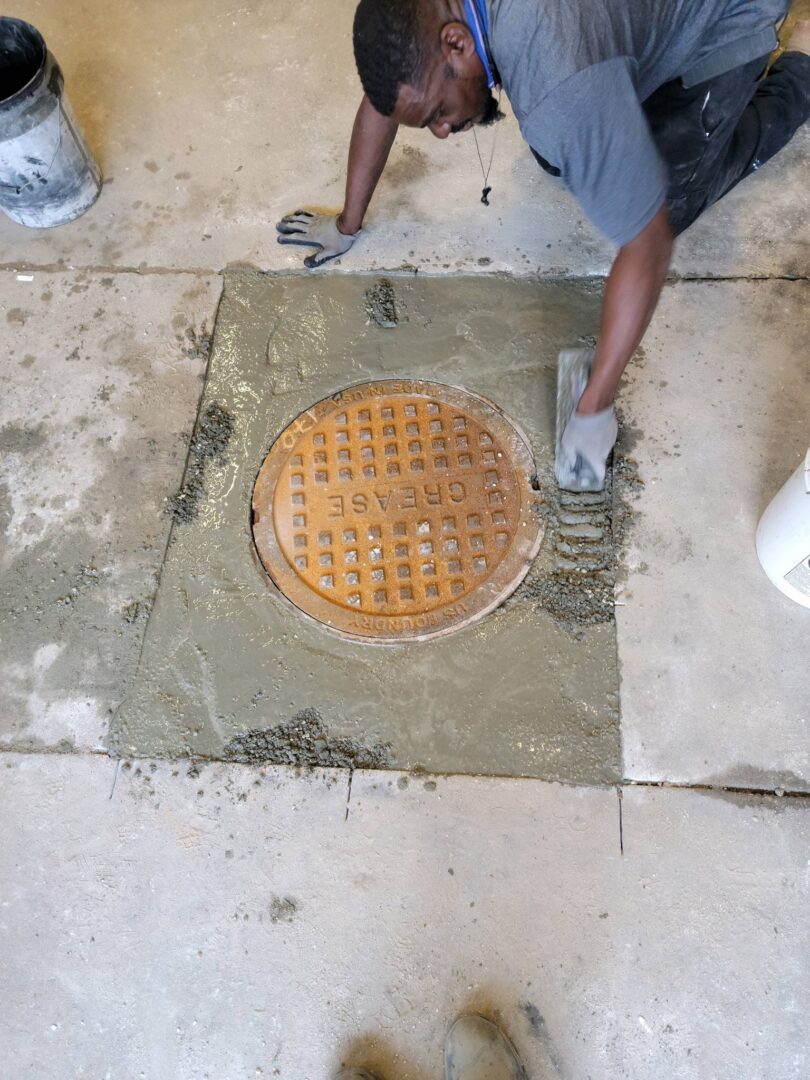 A man is cleaning the floor of an old manhole cover.