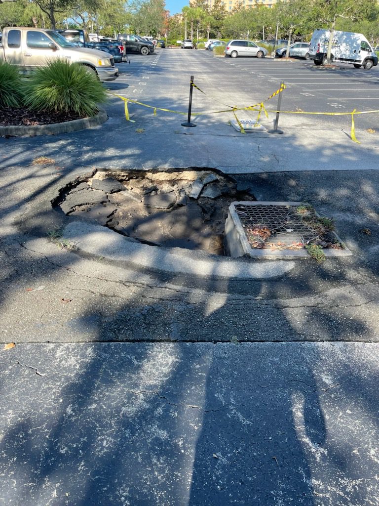 A hole in the ground that is sitting on the sidewalk.