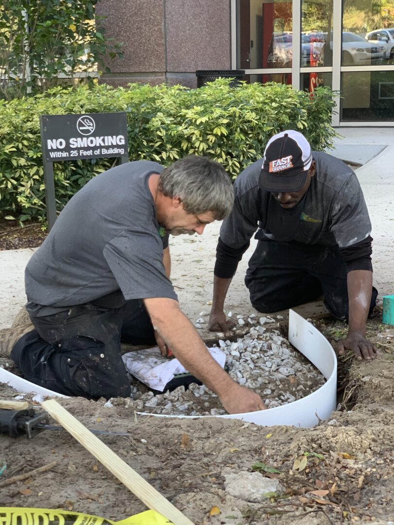 Two men working on a hole in the ground.